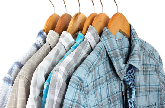 Shirts with ties on wooden hangers on light background