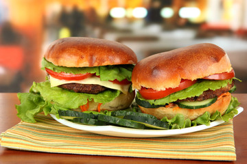 Big and tasty hamburgers on plate on table in cafe