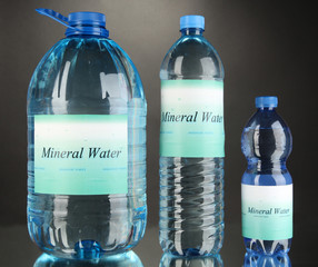 Different water bottles with label on grey background