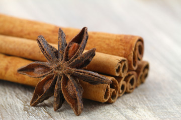 Star anise leaning against cinnamon sticks on wooden background