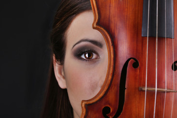 Beautiful young girl with violin on grey background