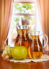 Apple juice in pitchers on table in room