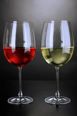 Red and white wine in glasses on grey background