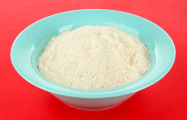Powdered milk in bowl for baby on red background