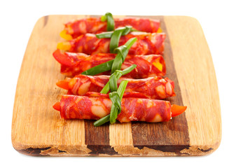 Salami rolls on wooden board, isolated on white