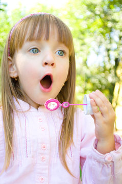 Little girl blowing soap bubbles