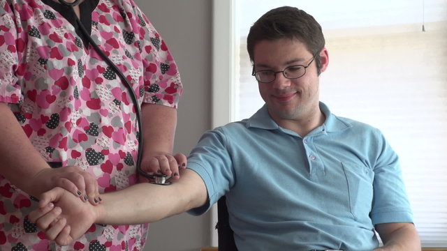 Man in wheelchair getting his pulse checked