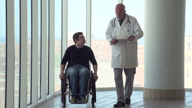 Man in wheelchair walking with doctor