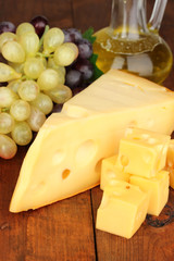 Cut cheese with grape on wooden table