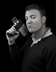 Naklejka premium man posing with cine film / video camera as a gun