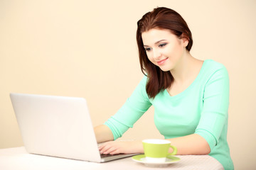Fototapeta premium Beautiful young woman working on laptop on light background