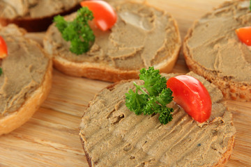 Fresh pate on bread on wooden board, close up