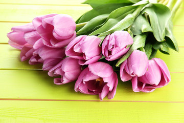 Beautiful bouquet of purple tulips on green wooden background