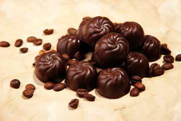 Chocolate candies and coffee beans, on beige paper background