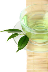 Transparent cup of green tea on bamboo mat, isolated on white