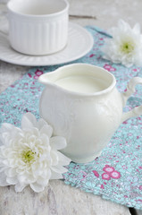 Obraz na płótnie Canvas Mleko w białe serwetką, kwiaty i filiżanki puste