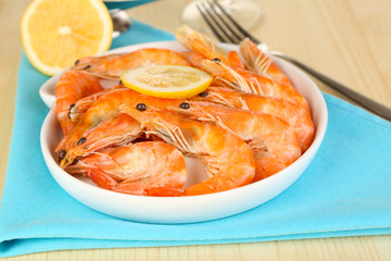 Shrimps with lemon on plate on wooden table close-up