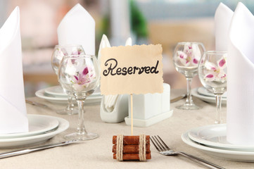 Reserved sign on restaurant table with empty dishes and glasses