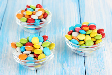 Colorful candies in glass bowls on blue wooden background