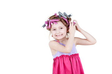 Little girl with  hair-curlers in her hair tries to remove one