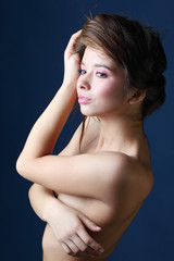 Beautiful sunburnt woman covers breast by hand and keeps hair.