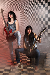 Sitting and standing women with electric guitar in studio