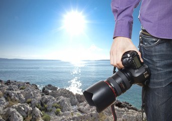 photographer's hand holding professional digital camera on rocky