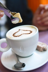 sugar cube is placed in a cup of cappuccino