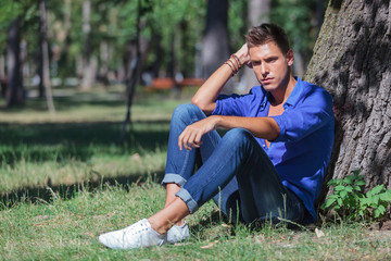 pensive man leaning on tree