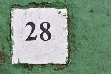 white tile with the number 28 on a green background painted ceme
