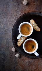 Two cups of espresso and cantuccini on a dark plate