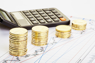 Downtrend stacks of coins, a calculator on the financial chart.