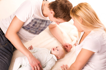 Young happy family: mother, father and baby lying