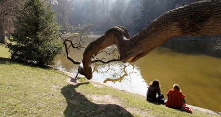 Deux femmes de dos au bord de l'eau avec branche