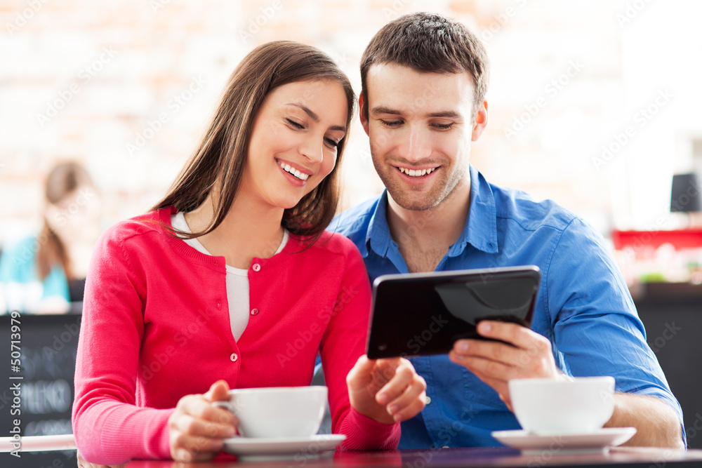 Wall mural couple using digital tablet in cafe