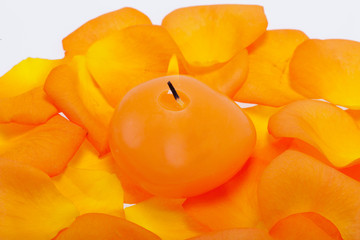 Spilt petals of the orange-rose around the aromatic candle