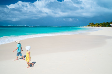 Fototapeta na wymiar Two kids walking along a beach at Caribbean