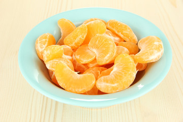 Tasty mandarine's slices in color bowl on light background