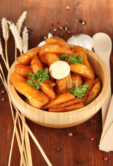Appetizing village potatoes in bowl on wooden table close-up