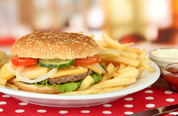 Tasty cheeseburger with fried potatoes, on bright background