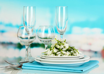 Serving dishes and snowdrops on blue natural background