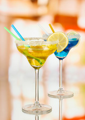 Yellow and blue cocktails in glasses on room background