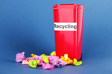 Recycling bin with papers on blue background