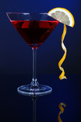 Red cocktail in martini glass on dark blue background