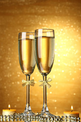 Two glasses of champagne on bright background with lights