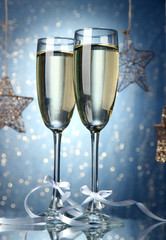 Two glasses of champagne on bright background with lights