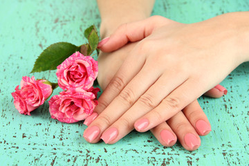 Woman hands with pink manicure and flowers, on color background