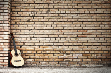 Fototapeta na wymiar gitara odpoczynku na ceglany mur