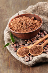 Cocoa powder and cocoa beans on wooden background