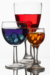 Glass wine glasses with multicolored liquid  on a white backgrou